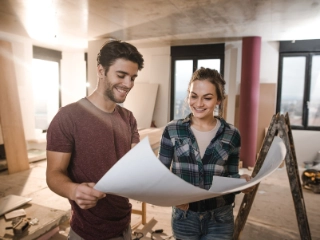 Paar studiert Bauplan in der Baustelle ihres Eigenheims